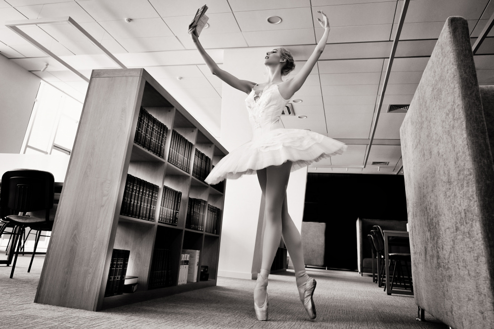 the Dreamer. ballerina on pointe shoes in the library reads a book holding it up von Alexandr