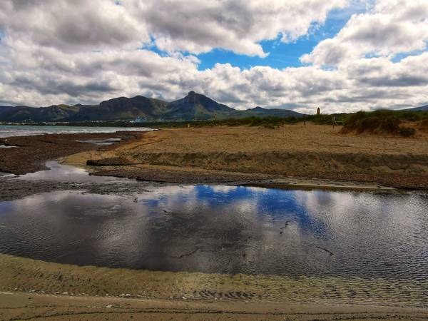 Weite Strandlandschaft mit Bergen - Spiegelung der Wolken im Wasser von Doris Beckmann