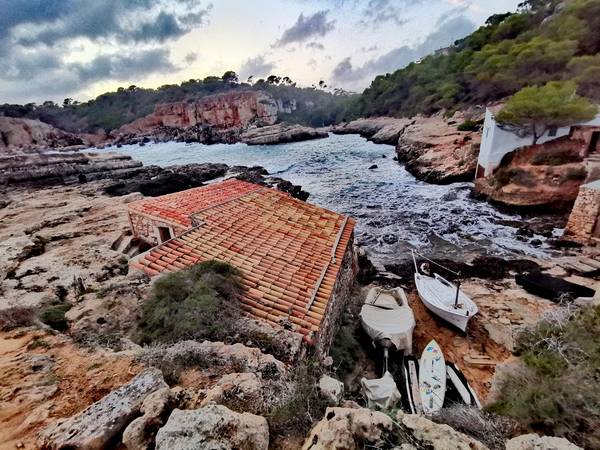 Wolken am Abend - Eine Felsenbucht mit Booten auf Mallorca von Doris Beckmann
