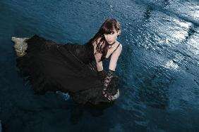 junge Frau auf einem Stein im Wasser