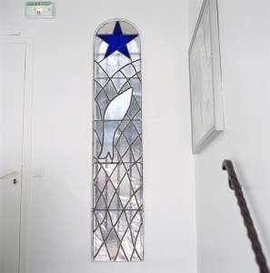 Stained glass window depicting a fish caught in a net beneath the Star of Salvation, from the stairs