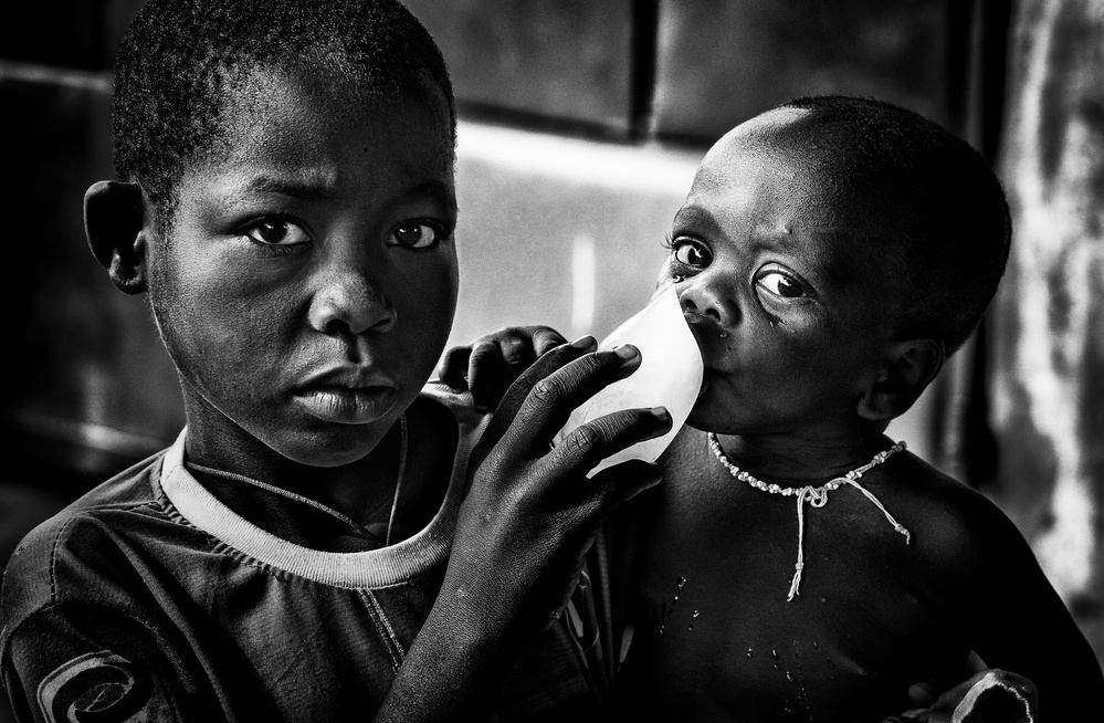 Quenching his brother´s thirst with a frozen water bag - Benin von Joxe Inazio Kuesta Garmendia