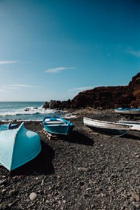 Blaue Boote auf schwarzem Vulkansstrand auf Lanzarote