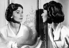 Actress Audrey Hepburn looking at her reflection in the mirror