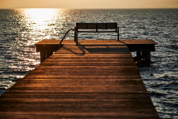Holzsteg mit Bank im Sonnenuntergang und Blick auf den Neusiedlersee von Robert Kalb