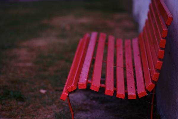 rote Holzbank vor einer Hauswand von Robert Kalb