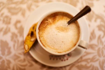 Eine Tasse Melange mit einer Cantuccini steht auf dem Tisch