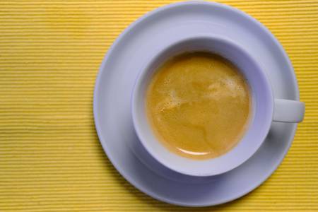 Kaffeetasse mit Kaffee auf gelbem Untergrund