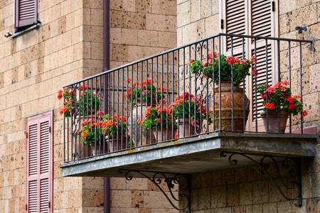Romantischer Balkon mit roten Blumen in Tonkrügen